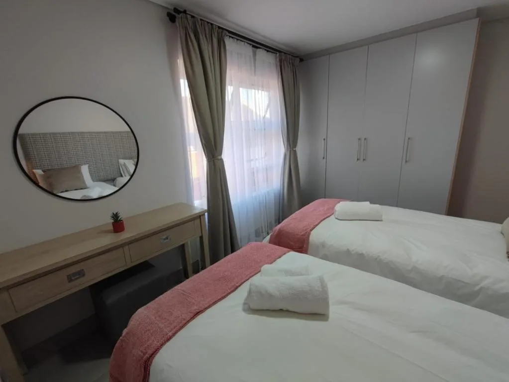Twin beds with white linens and pink runner in modern bedroom