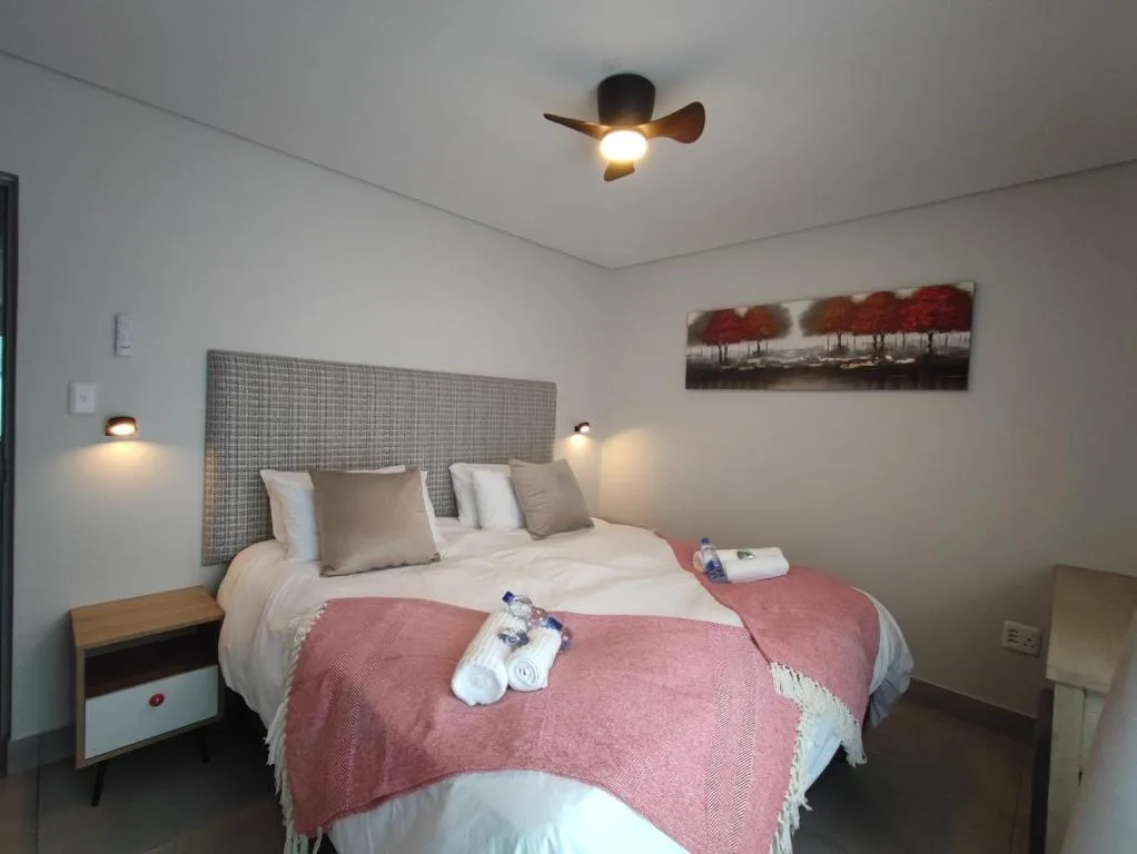 Modern bedroom with double bed, upholstered headboard, and ceiling fan