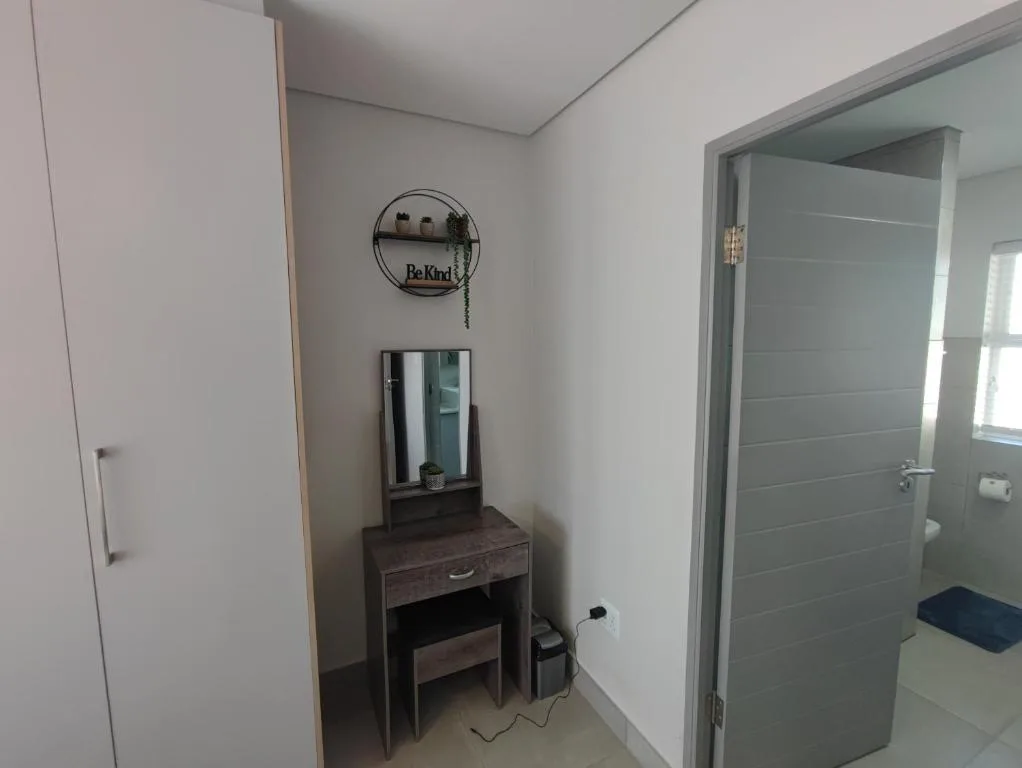 Modern bedroom with vanity desk, mirror, and ensuite bathroom entrance