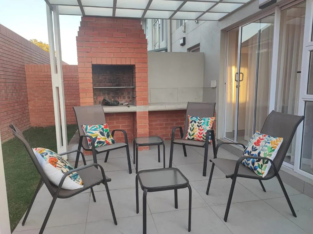 Covered patio with lounge chairs, colorful cushions, and brick fireplace