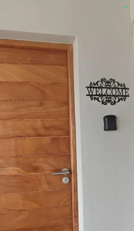 Welcome sign and doorbell on white wall beside wooden door