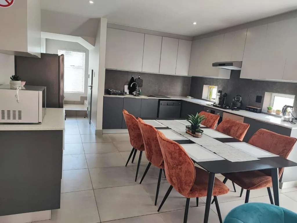 Modern dining table with rust-colored velvet chairs and open kitchen view