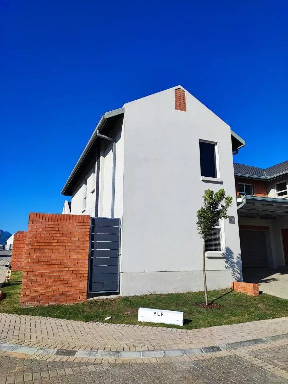 Modern white and brick duplex with dark blue gate and clear blue sky