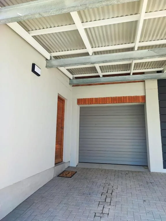 Garage entrance with corrugated metal roof and brick paver driveway