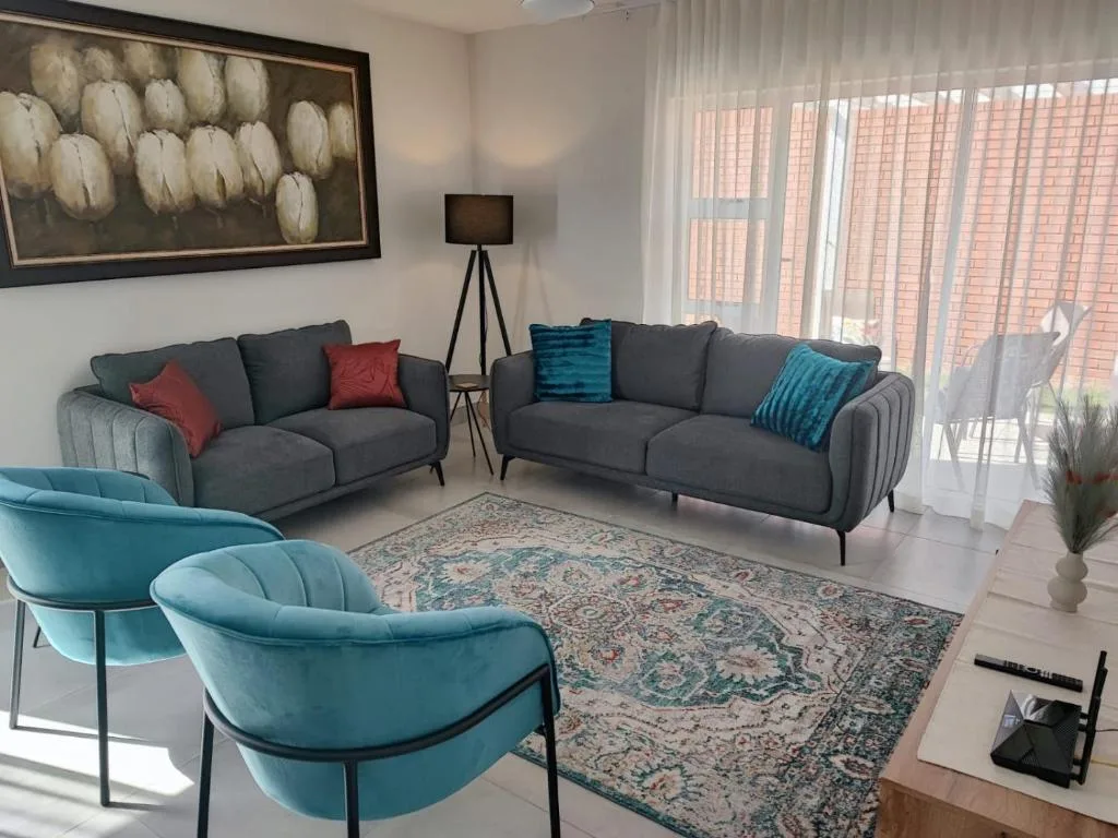 Modern living room with gray sofas, turquoise chairs, and decorative artwork