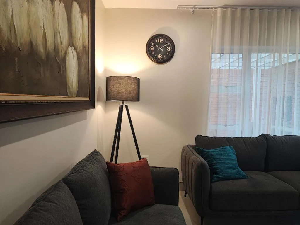 Modern lounge with dark sofas, tripod lamp, and wall clock