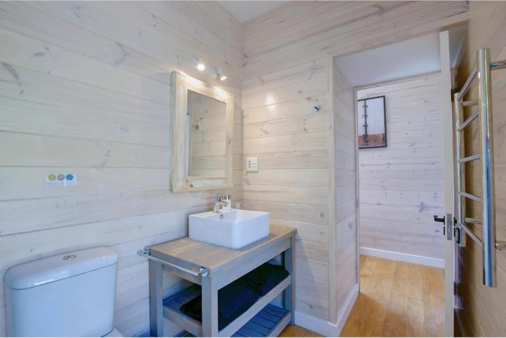 Bright bathroom with white vessel sink, mirror, toilet, and shower enclosure