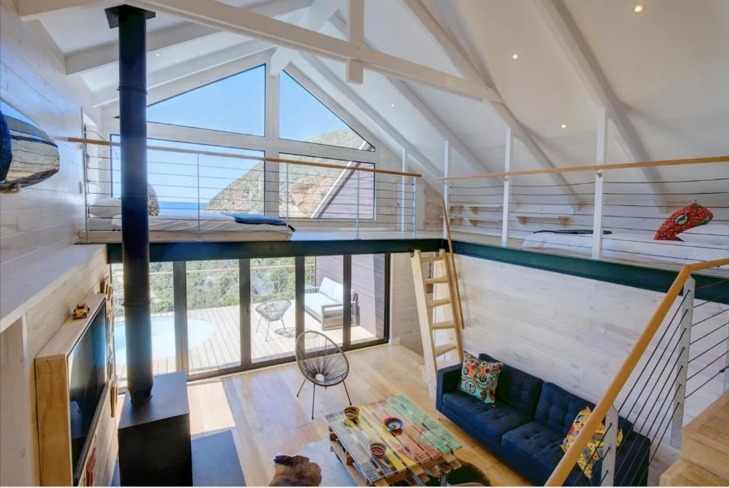 Loft bedroom with bunks, skylights, and ocean view through glass doors