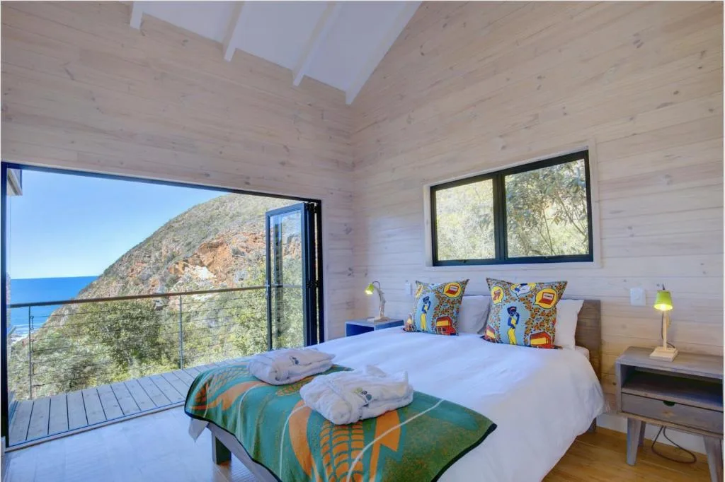 Bright bedroom with ocean view deck, modern furnishings, and coastal landscape