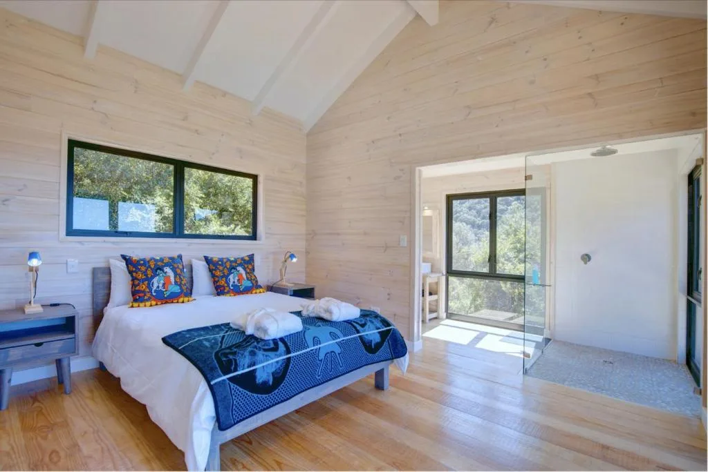 Spacious bedroom with queen bed, ensuite bathroom visible through glass doors