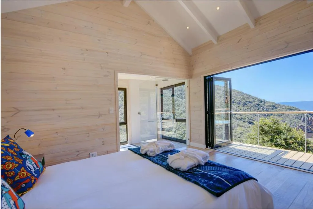 Spacious bedroom with wooden walls, bed, and mountain views through glass doors