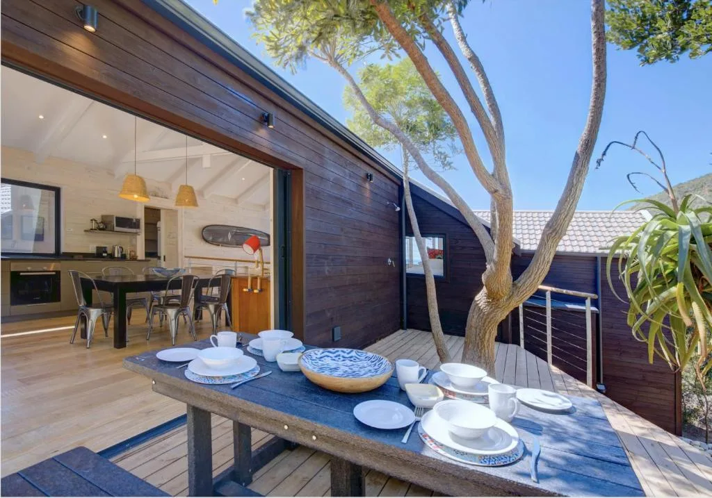 Outdoor dining table set under large tree with ocean view access