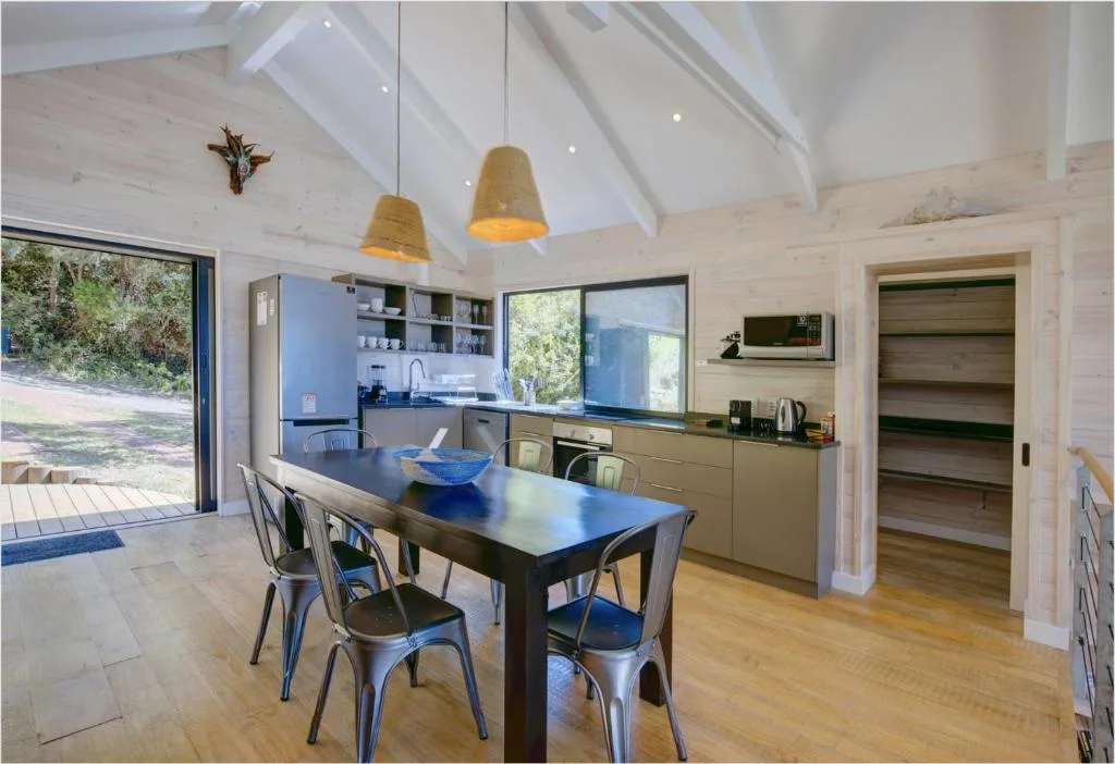 Modern dining area with black table, metal chairs, and open kitchen view