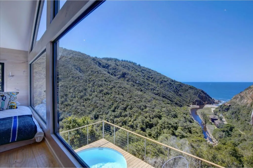 Scenic mountain and ocean vista from bedroom deck overlooking forested valley