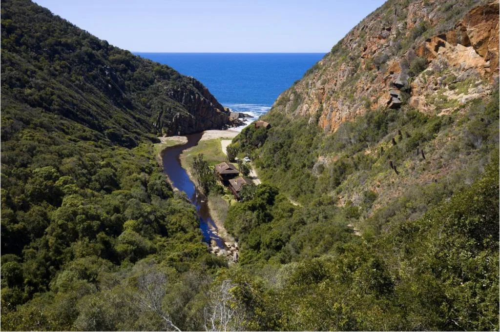Dramatic coastal valley view with river, cliffs, and ocean beyond