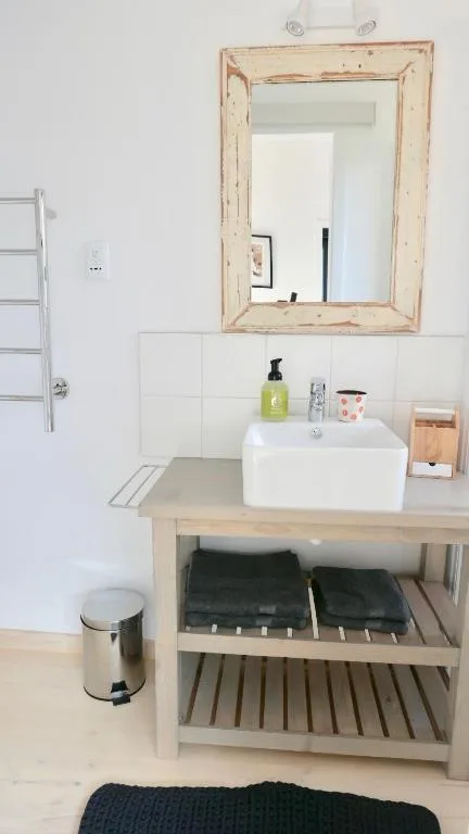 Clean bathroom vanity with white sink, wooden mirror frame, and storage shelves