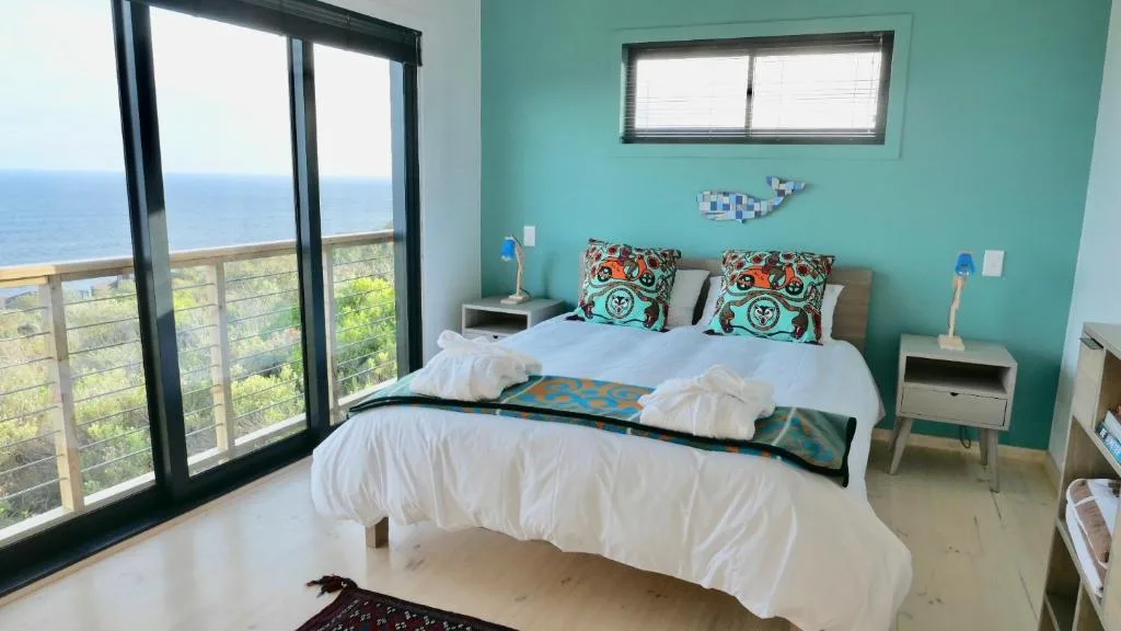 Bright turquoise bedroom with ocean views through glass doors and balcony