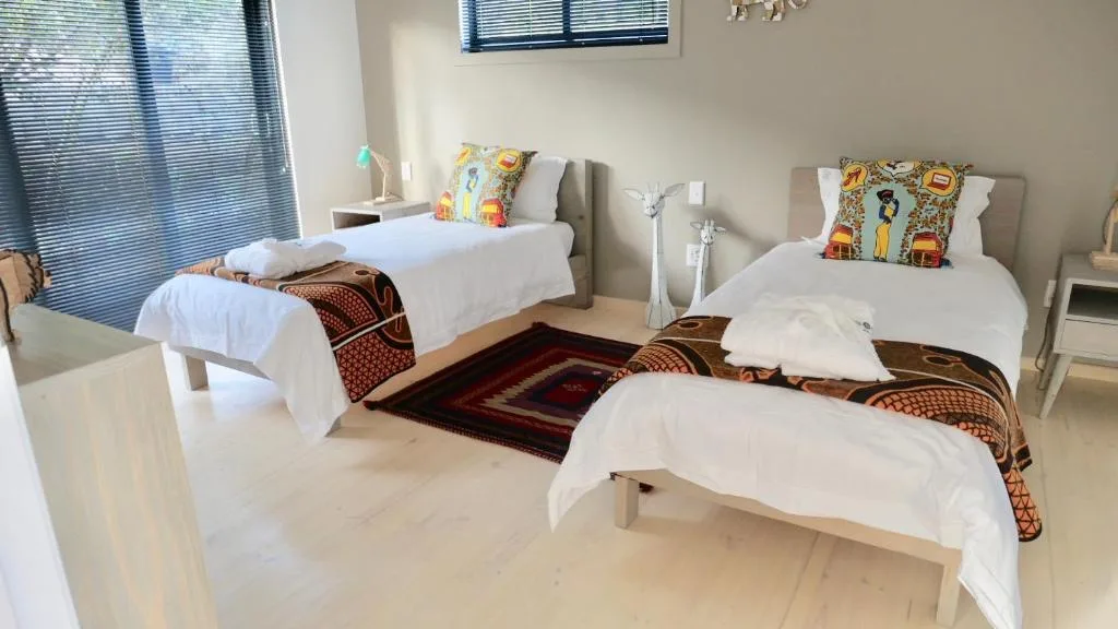 Spacious bedroom with three single beds, colorful pillows, and bright windows