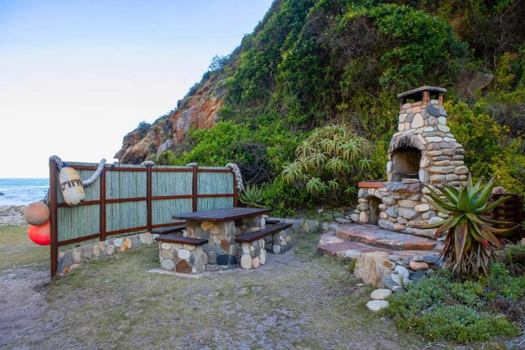 Beachfront braai area with stone fireplace and seating by the ocean