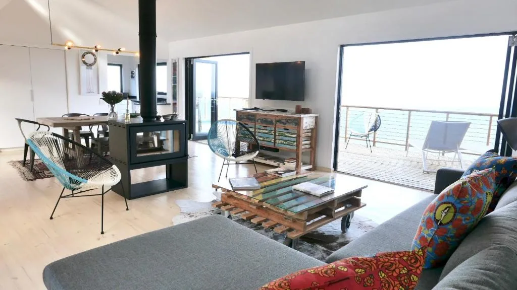 Modern lounge with sofa, fireplace, and glass doors opening to deck