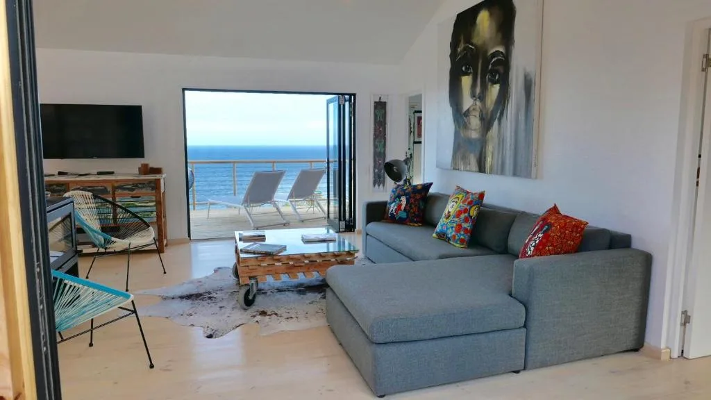 Modern lounge with gray sectional sofa facing ocean view through glass doors