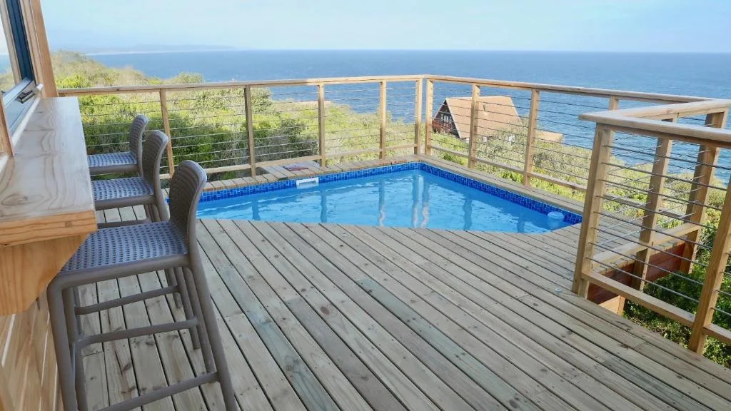 Elevated deck with swimming pool overlooking ocean and coastal landscape
