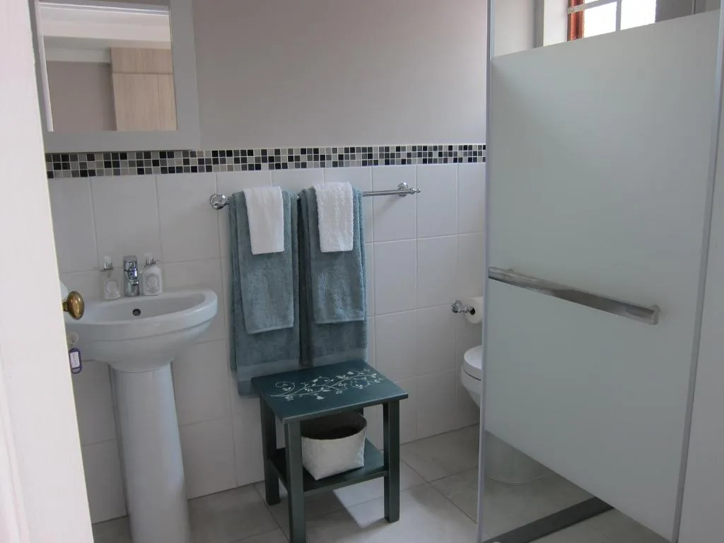 Modern bathroom with pedestal sink, toilet, and walk-in shower enclosure