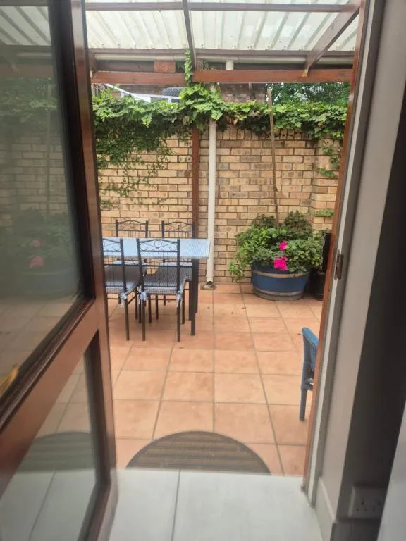 Covered patio with dining table, flowering plants, brick walls