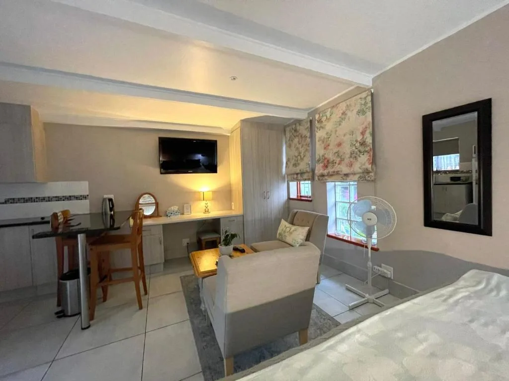Bright open-plan lounge with sofa, wall-mounted TV, and modern furnishings