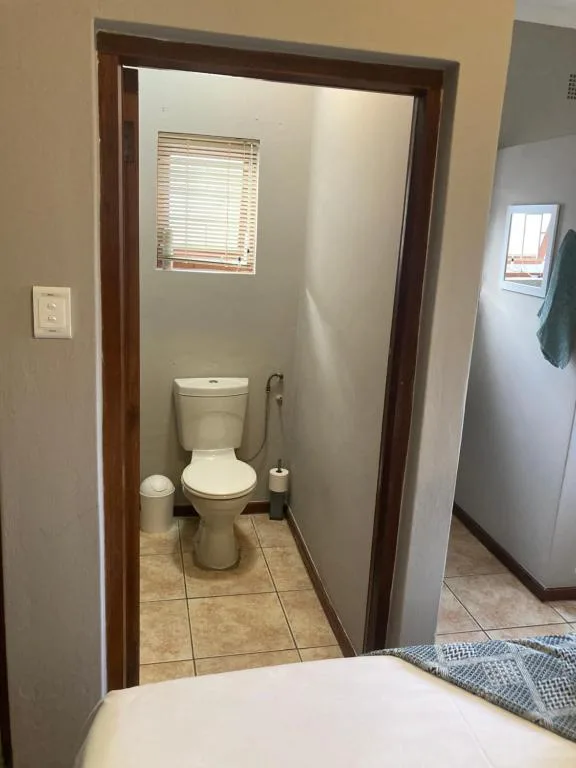 Small bathroom with toilet, window, and tiled flooring throughout
