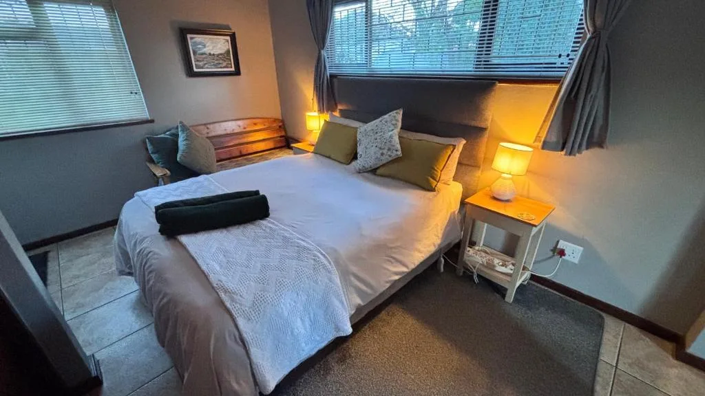 Warm-lit bedroom with queen bed, decorative pillows, and bedside lamps