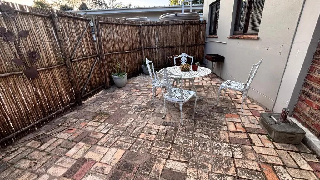 Enclosed patio with decorative metal table and chairs, reed fencing