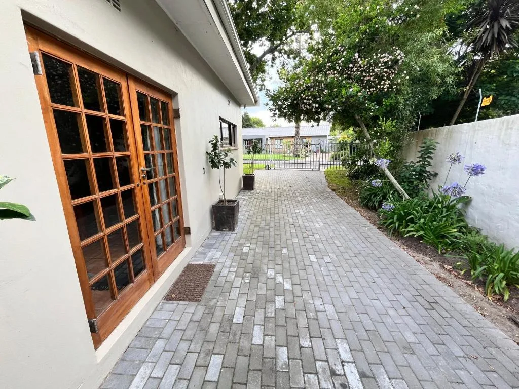 White cottage exterior with wooden doors and paved driveway entrance