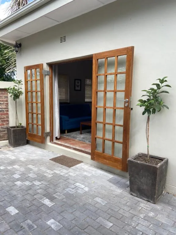 White cottage entrance with wooden glass doors and potted plants