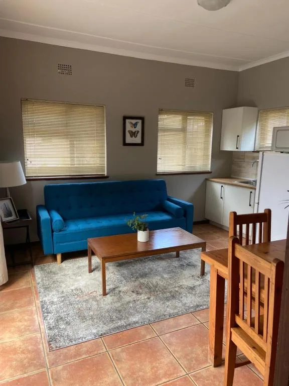 Bright lounge with blue sofa, wooden coffee table, and kitchenette