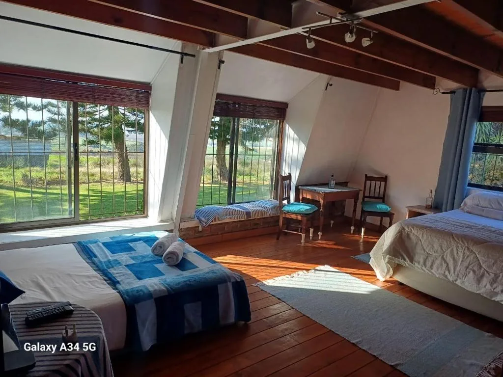 Spacious bedroom with multiple beds and large windows overlooking green countryside