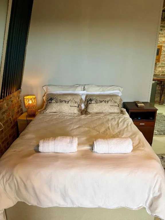 Spacious bedroom with queen bed, white linens, and bedside lamp