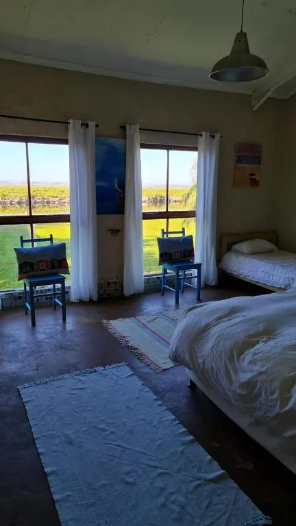 Bright bedroom with two beds and large windows overlooking countryside
