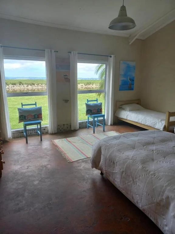 Spacious bedroom with two beds, large windows overlooking lagoon and gardens