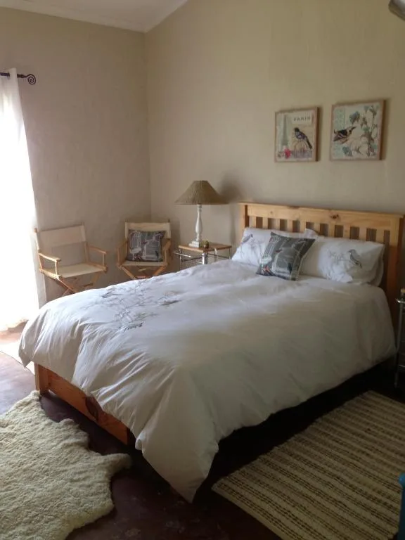 Bright bedroom with wooden bed, white linens, decorative pillows, and framed artwork