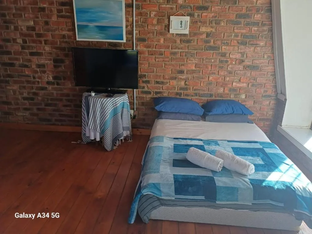 Spacious bedroom with double bed, rolled towels, TV, and exposed brick walls