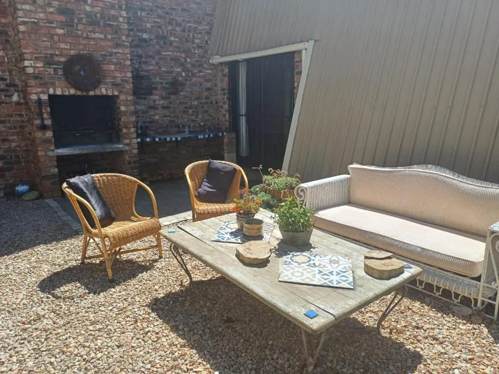Outdoor patio with wicker seating and wooden table overlooking garden area