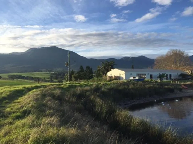 Modern blue and white countryside house with mountain backdrop and water feature