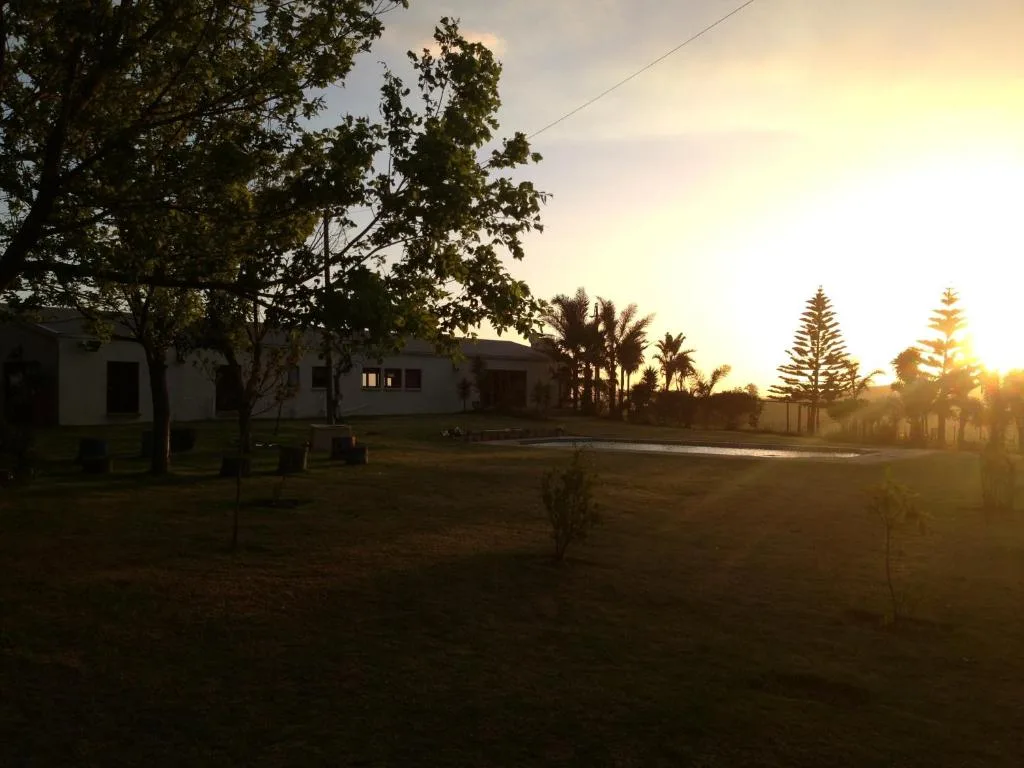 Spacious countryside property at sunset with manicured grounds and native trees