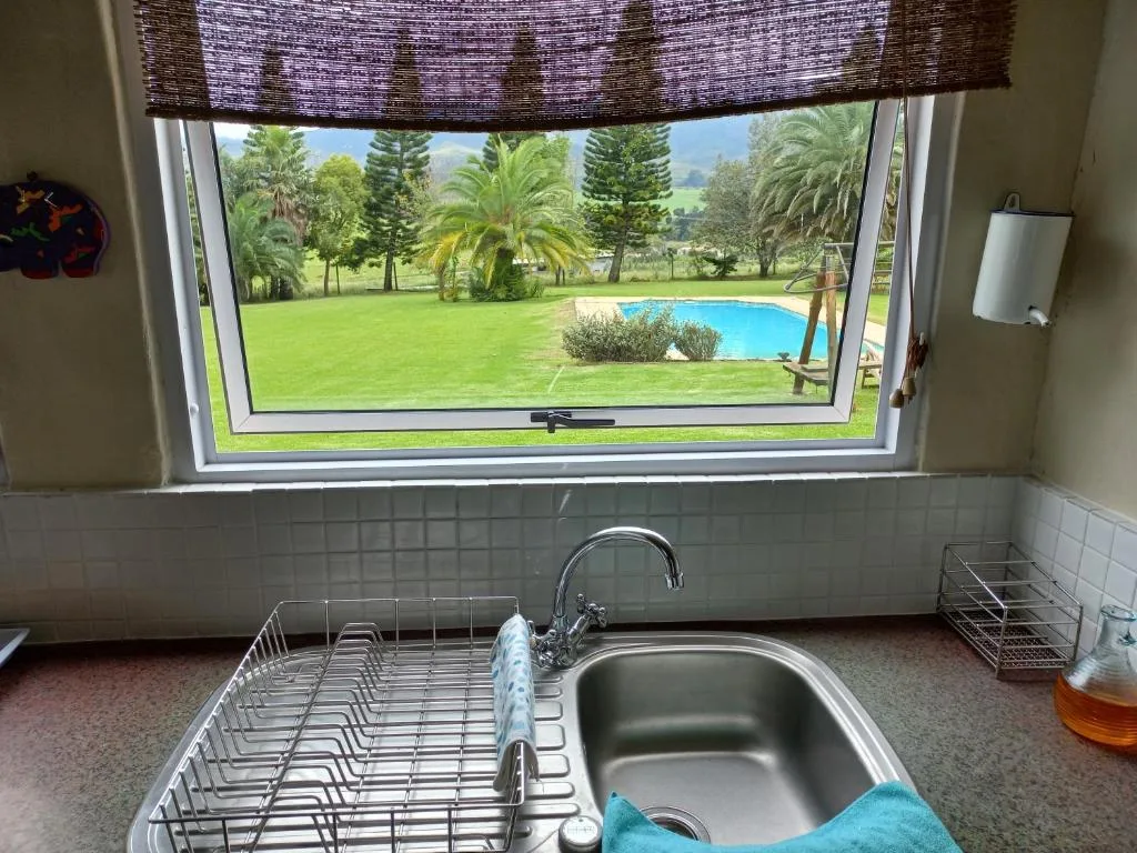 Kitchen sink with window overlooking manicured gardens and swimming pool