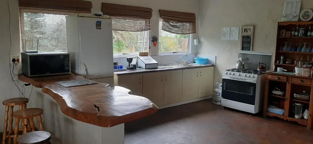 Open-plan kitchen with wooden counter, appliances, and large windows