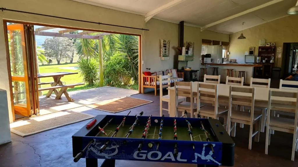 Open-plan lounge with foosball table and dining chairs, garden view