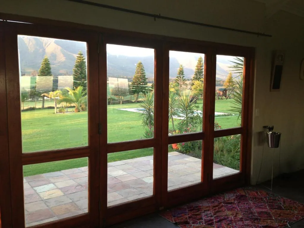 Mountain landscape and manicured garden visible through large sliding glass doors