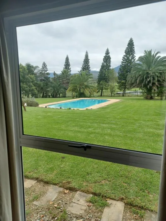 Swimming pool and manicured lawn framed by mountains and tall pine trees