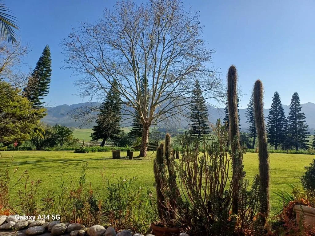 Manicured garden overlooks vast valley with mountains and lush green fields beyond